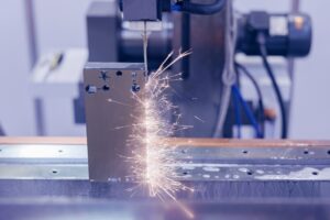 Elektroerozivní drátová řezačka vyřezávající tvar ozubeného kola do střižné vložky, průmysl CNC strojů.