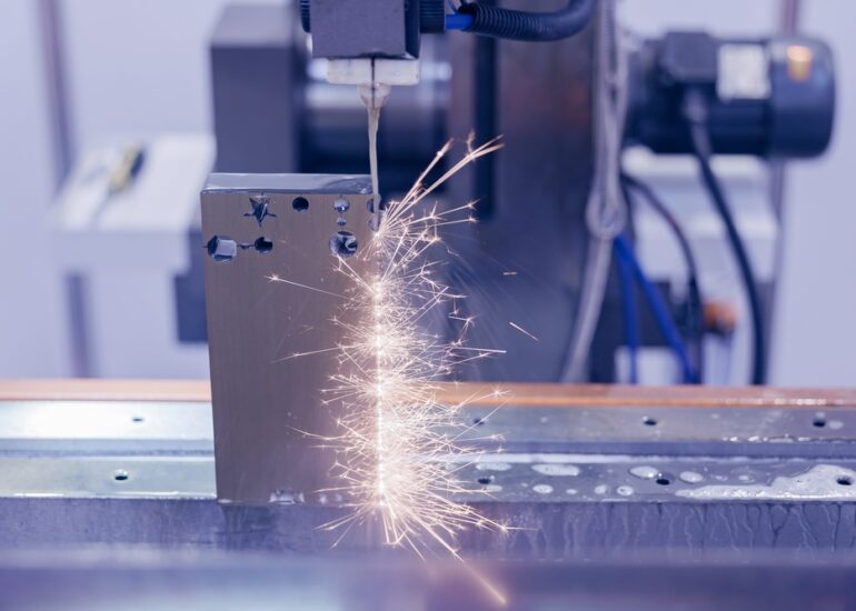 Elektroerozivní drátová řezačka vyřezávající tvar ozubeného kola do střižné vložky, průmysl CNC strojů.