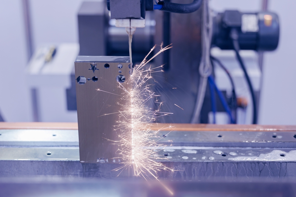 Elektroerozivní drátová řezačka vyřezávající tvar ozubeného kola do střižné vložky, průmysl CNC strojů.